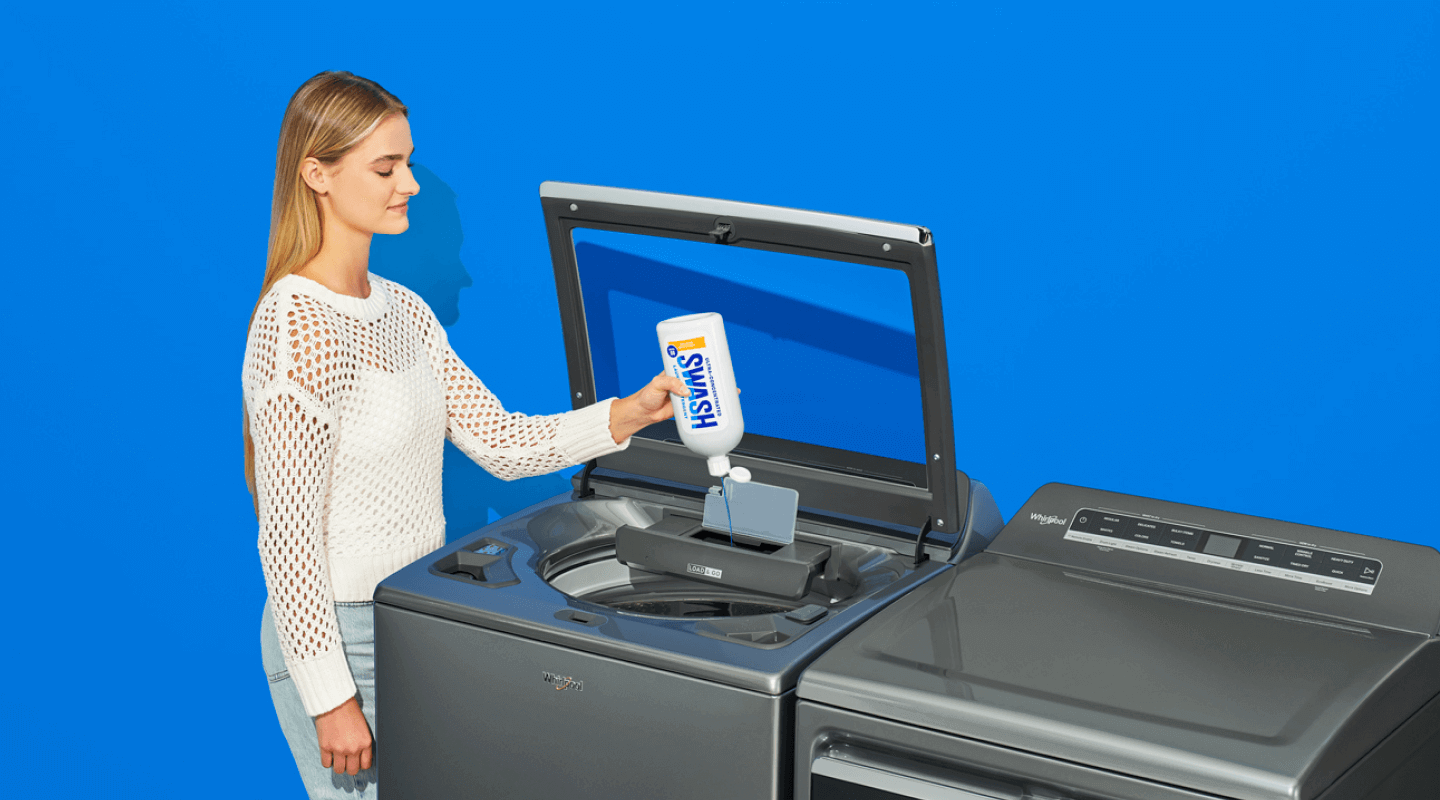 A woman dispensing Swash laundry detergent directly into a top loading washing machine using the Precision Pour Cap