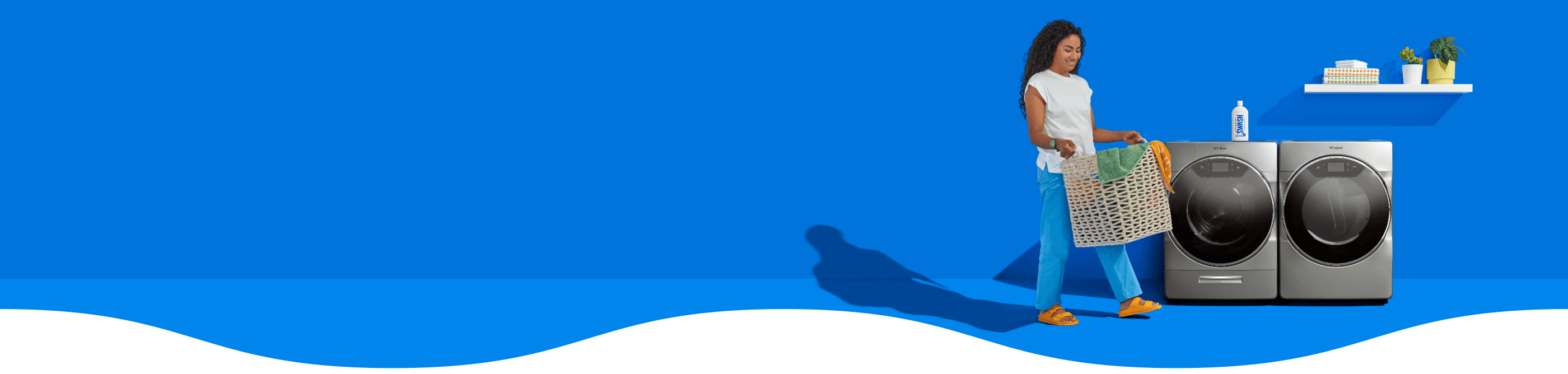 Woman carrying a basket of laundry infront of a Whirlpool® Washer and Dryer