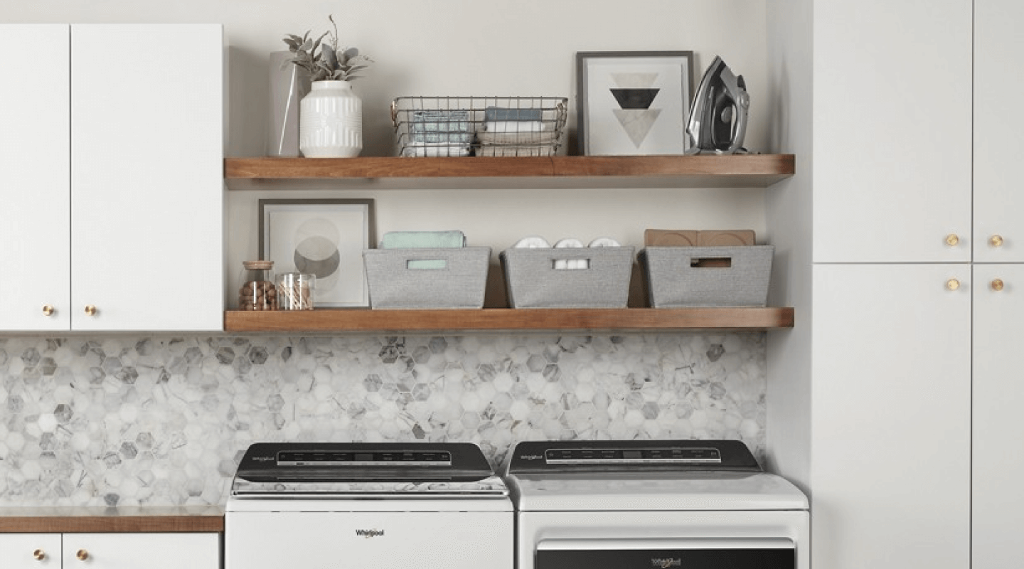 A neatly organized launndry room with a Whirlpool® waaher and dryer.