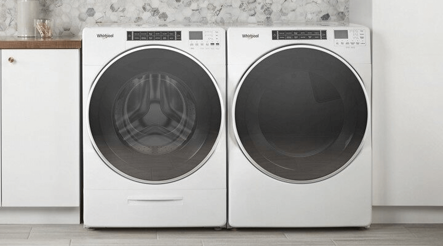 A front load Whirlpool® washer and dryer in a laundry room with white white cabinets