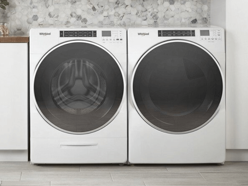 A front load Whirlpool® washer and dryer in a laundry room with white white cabinets
