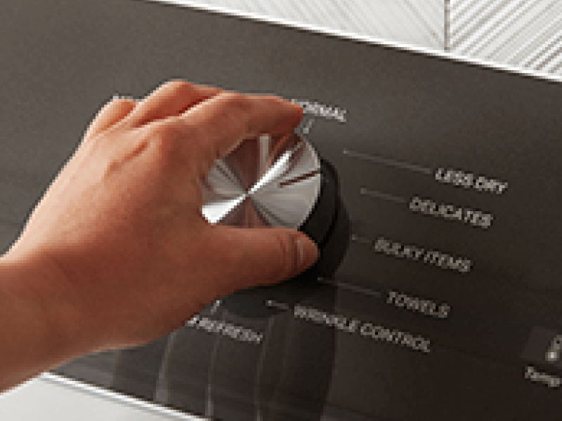 A person adjusts the dial on a Whirlpool dryer.