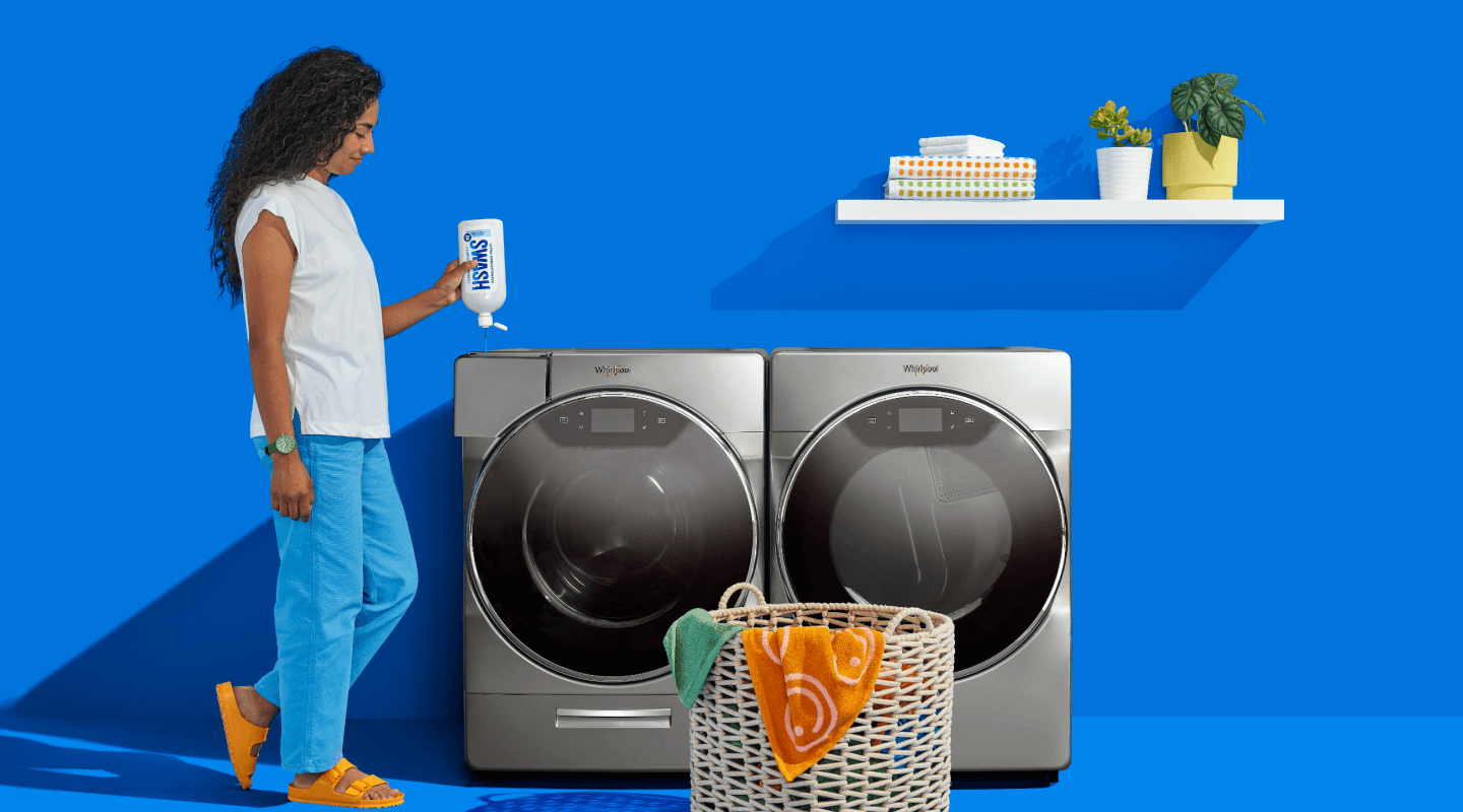 A woman filling a Whirlpool® front load washer with Swash® Laundry Detergent.