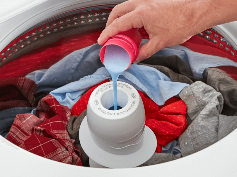 A person adding liquid detergent to a washing machine