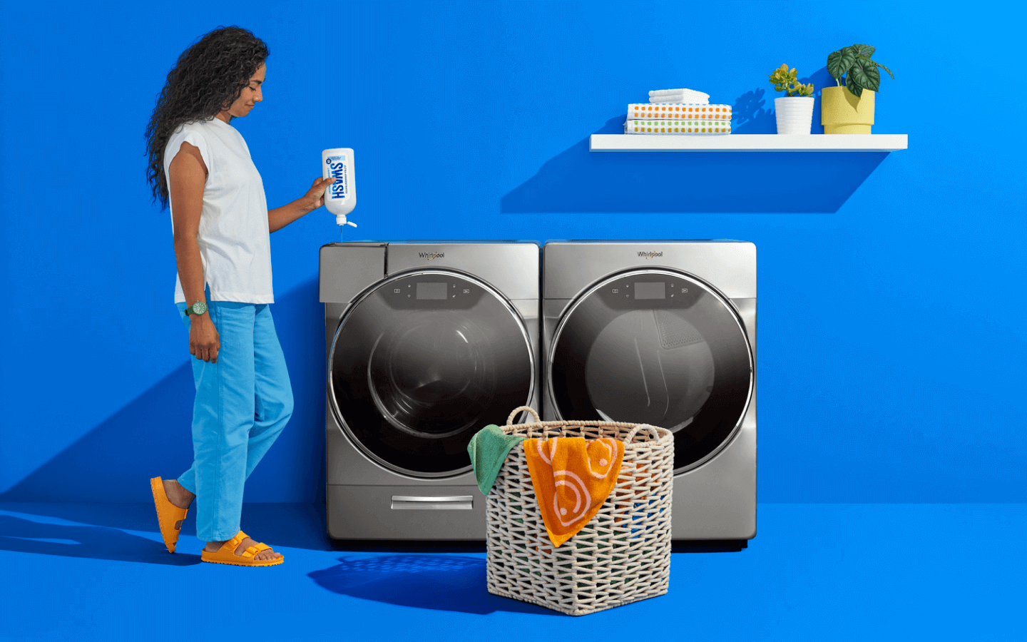 A woman filling a Whirlpool® front load washer with Swash® Laundry Detergent.