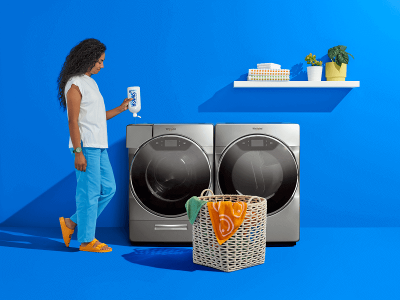 A woman filling a Whirlpool® front load washer with Swash® Laundry Detergent.